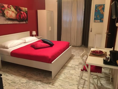 Camera da letto moderna a Domum Vaticani Roma con biancheria rossa, struttura bianca e pavimento in marmo