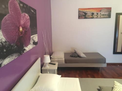Camera da letto moderna a Domum Vaticani Roma con opera d'arte orchidea viola, letto grigio, lampada comodino bianca