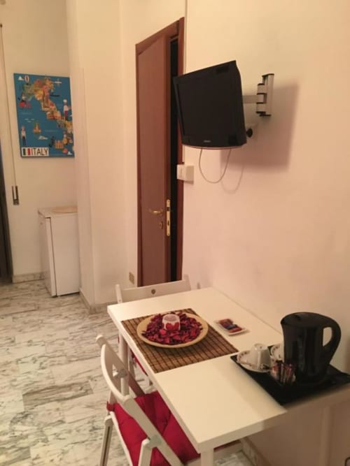 Camera doppia Domum Vaticani Roma con tavolo da pranzo, TV a parete, poster di viaggio italiano e bollitore sulla scrivania