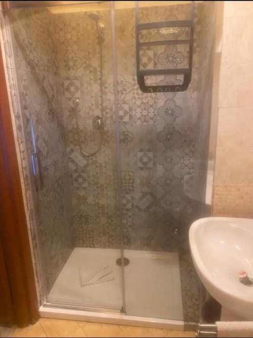 Moderna cabina doccia con piastrelle decorative e base bianca nel bagno dell'hotel Domum Vaticani Roma, accanto al wc bianco