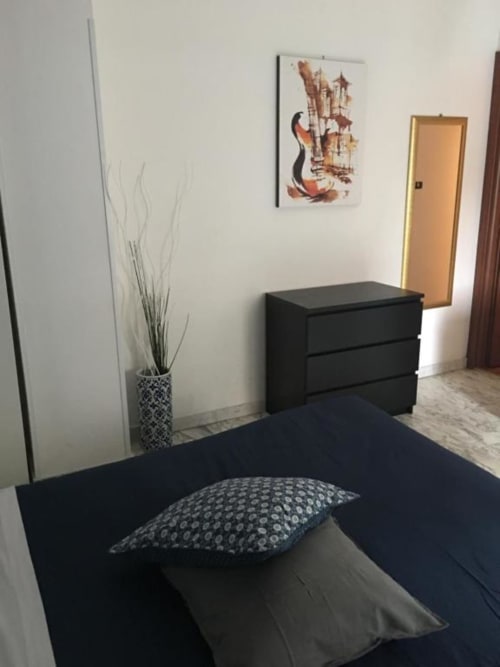 Camera Standard Doppia moderna presso Domum Vaticani Roma con letto nero, cuscino decorato, comò nero, pianta in vaso e opere d'arte