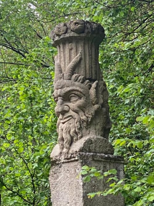Scultura in pietra di uomo barbuto circondata da edera verde presso l'hotel Domum Vaticani a Roma