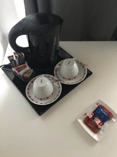 Vassoio di benvenuto hotel con bollitore elettrico nero, due tazze da tè bianche con piattini, bustine di tè e caffè a Domum Vaticani Roma