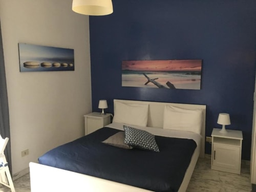 Camera matrimoniale moderna presso Domum Vaticani B&B Roma con pareti blu navy, opere d'arte a tema marino e biancheria color crema.