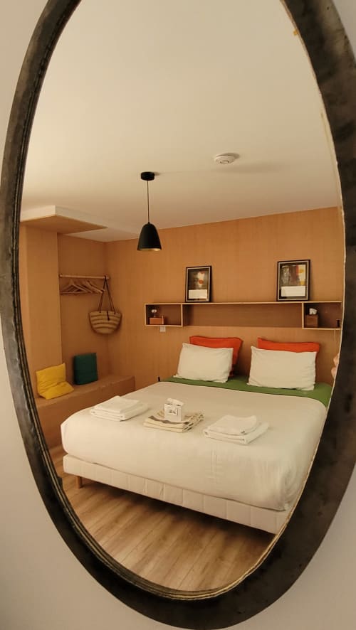 Chambre moderne aux murs orange au Lodge du Cap Ferret, avec lit blanc et oreillers orange, rangements intégrés