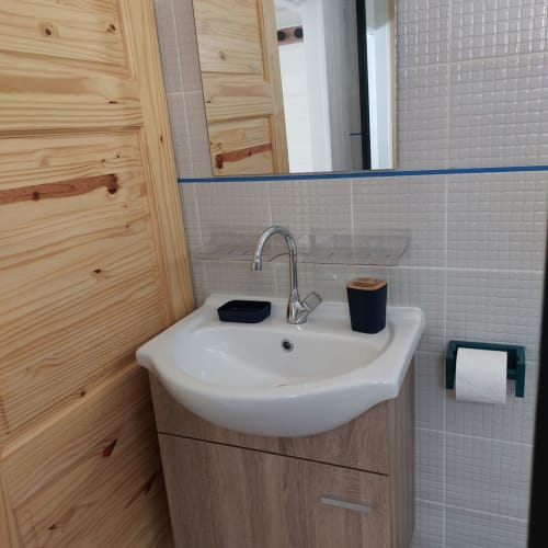 Salle de bain moderne avec lavabo blanc, meubles en bois et murs carrelés du bungalow Coco Guadeloupe, Terre de Haut