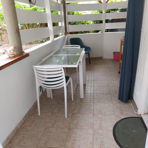 Terrasse couverte avec table en verre et chaises rayées au bungalow Coco Guadeloupe, Terre-de-Haut, Les Saintes