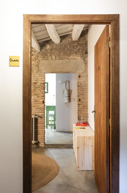 Entrada de la habitación Charlotte en Casa Merceditas, Corçà, con puerta de madera y paredes de piedra vista