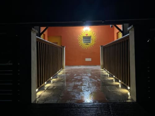 Terrasse couverte illuminée du Caress'antillaise à Deshaies avec mur orange et sculpture solaire décorative