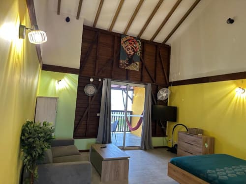 Élégant appartement moderne à Caress'antillaise à Deshaies, aux murs jaunes, poutres bois, séjour et accès terrasse