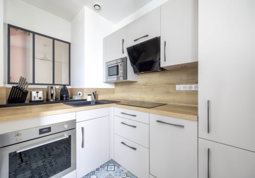 Cuisine moderne de l'appartement d'Épernay avec placards blancs, comptoirs en bois et appareils en acier inoxydable