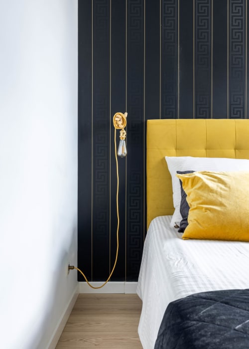 Chambre moderne à Secrets de Chef de Cave à Épernay avec tête de lit jaune, mur à motifs noirs et applique dorée