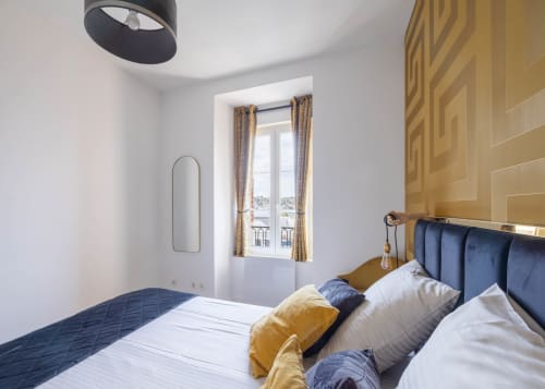 Chambre moderne à Secrets de Chef de Cave à Épernay avec tête de lit en velours bleu, mur d'accent doré et vue sur la ville