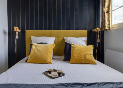 Chambre luxueuse au Secrets de Chef de Cave à Épernay, avec tête de lit dorée, coussins jaunes et papier peint à rayures foncées