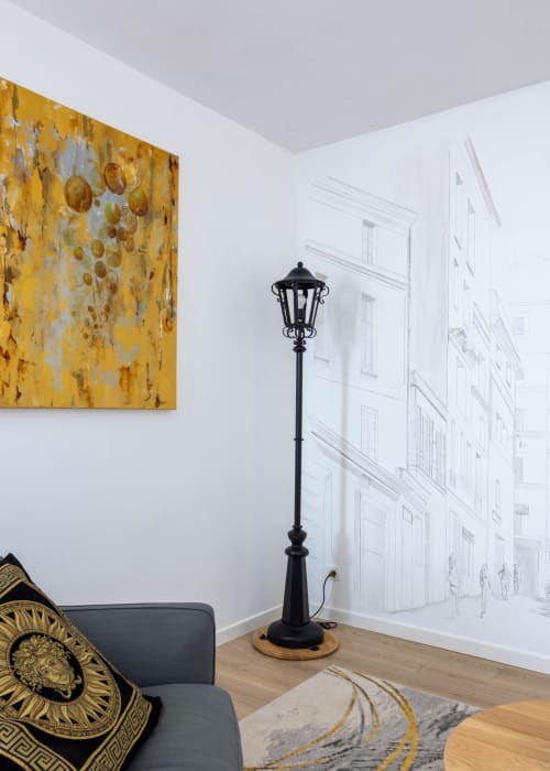 Intérieur d'appartement moderne aux Secrets de Chef de Cave à Épernay avec œuvre dorée, lampadaire noir et fresque architecturale
