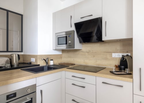 Cuisine moderne de l'appartement La Bulle Dorée aux Secrets de Chef de Cave, Épernay, avec mobilier blanc et plan de travail en bois