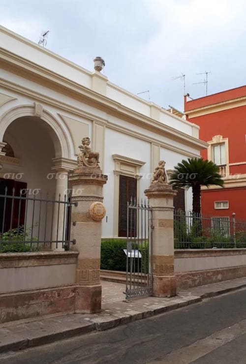 Historic villa entrance with stone columns and sculptural details in Nardò, Puglia