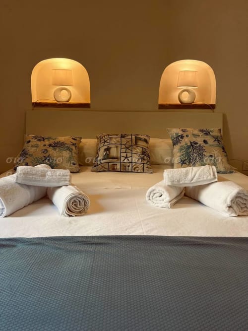 Letto matrimoniale elegantemente preparato nella villa Puglia Estate con asciugamani arrotolati, cuscini decorativi e illuminazione ambientale