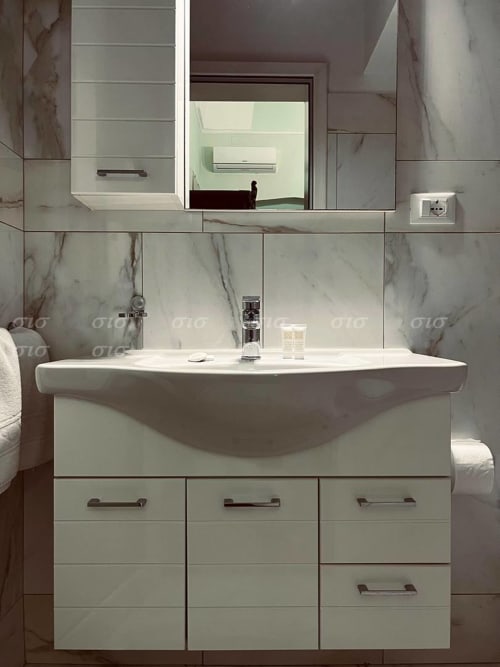 Bagno moderno a Villa degli Angeli, Puglia con rivestimenti in marmo, lavabo bianco e specchio