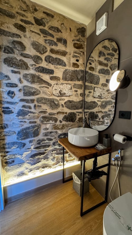 Bagno moderno presso la Talking Stones B&B a Dolceacqua con muro in pietra rustica, lavabo a ciotola e finiture contemporanee.