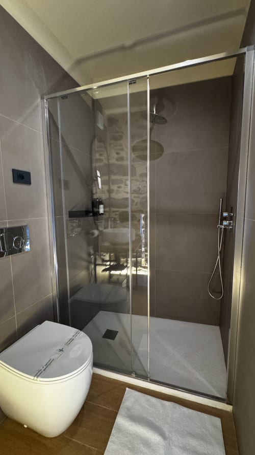 Bagno moderno presso il Talking Stones B&B a Dolceacqua con doccia a filo pavimento, wc e pareti rivestite in piastrelle