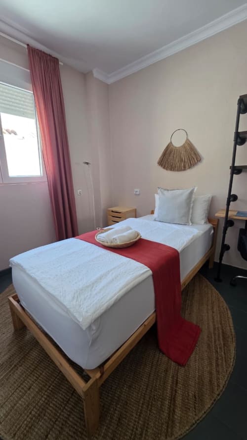 Ostro room at Casa de Océano, Tarifa with twin beds, red runner, woven decor, and window with pink curtains