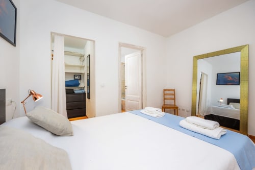 Dormitorio luminoso en Apartamento Jaume B, Artà, con cama de matrimonio, espejo, silla de madera y acceso a baño privado