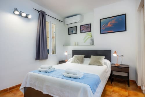 Dormitorio luminoso en Apartamento Jaume B, Artà con cama doble, cabecero oscuro, sábanas blancas, aire acondicionado y decoración de madera
