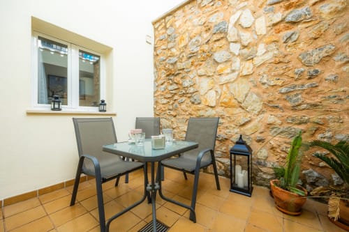 Patio con muro de piedra en Apartamento Jaume B, Artà centro - zona de estar al aire libre con mesa y sillas