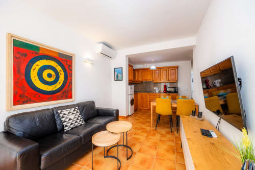 Sala moderna en Apartamento Jaume B, Artà con sofá de piel negra, mesa de madera, suelos de baldosa naranja