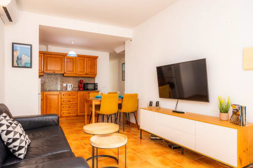 Luminoso salón en Apartamento Jaume B, Artà con cocina naranja, TV de pantalla plana, sofá de cuero y comedor