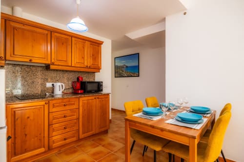 Cocina-comedor moderno en Apartamento Jaume B, Artà con muebles de madera, vajilla azul y sillas amarillas