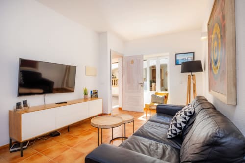 Sala moderna en Apartamento Jaume B, Artà con sofá de cuero negro, TV pantalla plana, muebles de madera y tonos terracota