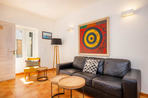 Sala de estar moderna en Apartamento Jaume B, Artà con sofá de cuero oscuro, arte abstracto colorido y mesa de café de madera
