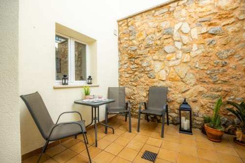 Zona de estar en la terraza del Apartamento Jaume B, Artà con pared de piedra, sillas, mesa y ventana