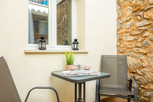 Acogedor rincón de terraza en Apartamento Jaume B de Artà con mesa, sillas, plantas en macetas y pared de piedra rústica