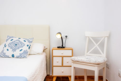 Dormitorio acogedor en Apartamento Jaume B, Artà con cabecero crema, almohada azul estampada, mesita de noche de madera, silla de escritorio y