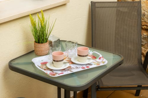 Terraza exterior del Apartamento Jaume B en Artà con dos tazas de café, planta decorativa y cómoda silla