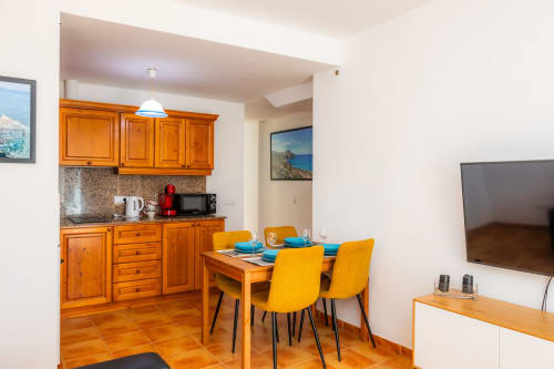 Cocina y comedor modernos en Apartamento Jaume B, Artà con muebles de madera, sillas amarillas y cocina equipada