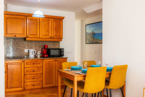 Cocina y comedor del Apartamento Jaume B, Artà, con muebles de madera, sillas amarillas y mesa lista para los huéspedes.