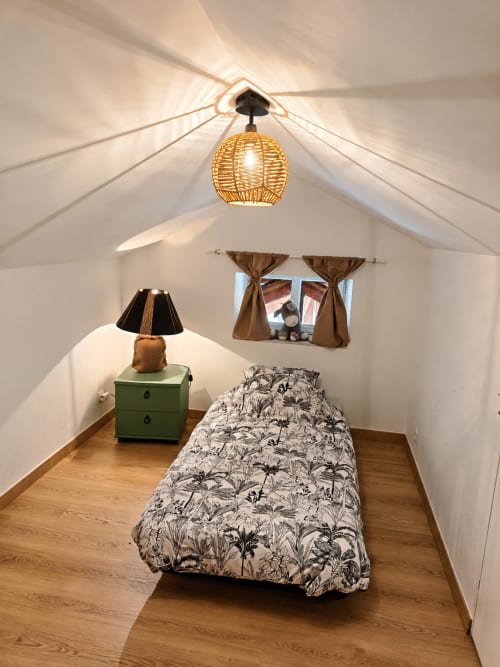 Cozy bedroom in Domaine de Beau Site gîte with single bed, wicker ceiling light, green nightstand, and window with brown