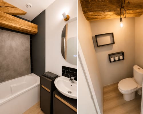 Modern bathroom at Domaine de Beau Site with white toilet, round mirror, wooden beams, black accents and warm lighting