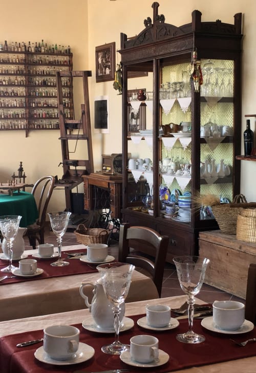 Elegante sala da pranzo dell'Hotel Candalú con tavolo apparecchiato, mobile vintage e collezione di liquori antichi in esposizione