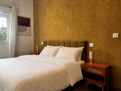 Chambre de la villa Casa Loc Conciergerie à Calenzana avec mur jaune moutarde, tête de lit capitonnée, literie crème