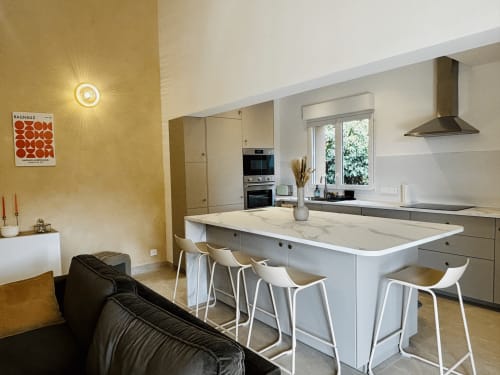 Cuisine moderne et salle à manger de la villa Casa Loc Conciergerie à Calenzana avec îlot en marbre et électroménagers inox
