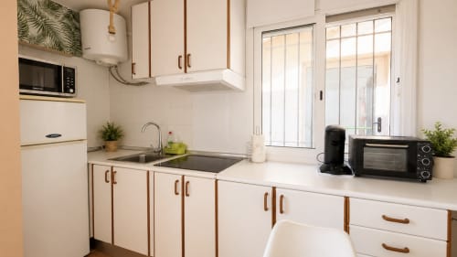 Cocina moderna con muebles blancos, fregadero de acero inoxidable y vistas a la ciudad en Holidays Costa Brava, Empuriabrava