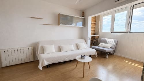 Salón luminoso en apartamento de Holidays Costa Brava con sofá crema, mesita blanca y vistas panorámicas de la ciudad