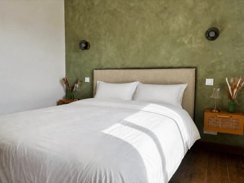 Chambre moderne de la villa Casa Loc Conciergerie à Calenzana avec murs vert sauge, tête de lit capitonnée beige et blanc