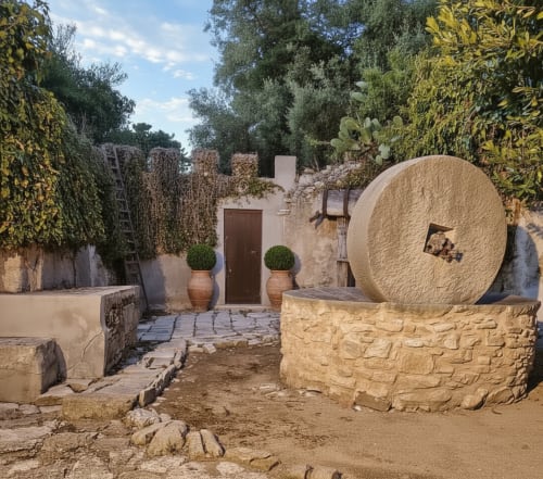 Cortile dell'Hotel Candalú a Valderice con grande macina in pietra, architettura rustica e muri ricoperti di edera