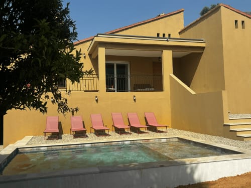 Villa jaune avec piscine et transats roses dans la campagne de Calenzana